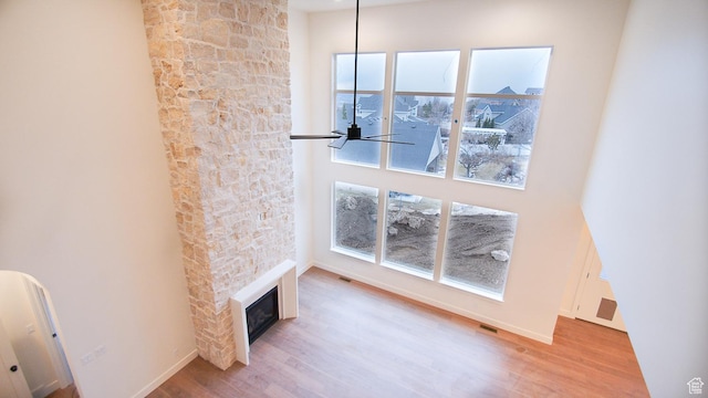 unfurnished living room with wood finished floors, a fireplace, a ceiling fan, and baseboards