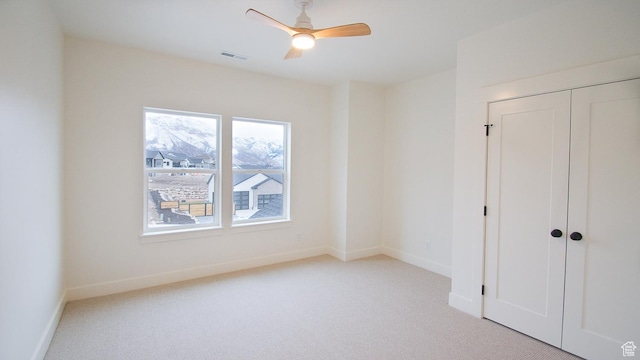 unfurnished bedroom with carpet floors, baseboards, a closet, and ceiling fan