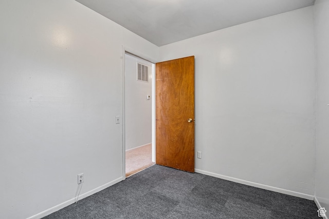 spare room featuring dark carpet and baseboards