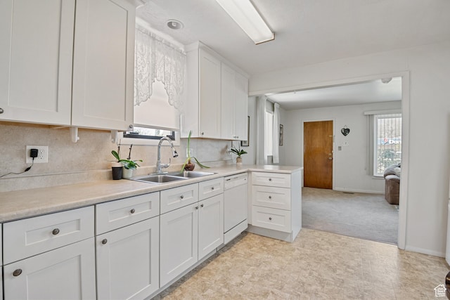 kitchen with a sink, dishwasher, white cabinets, and light countertops
