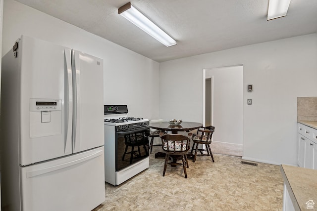 kitchen with white appliances, white cabinets, and light countertops