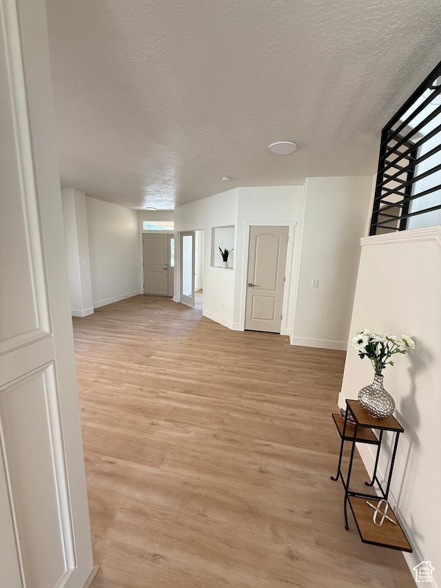 7038 W 8090 S, West Jordan, UT 84081 - unfurnished living room featuring a textured ceiling, baseboards, and light wood-style flooring