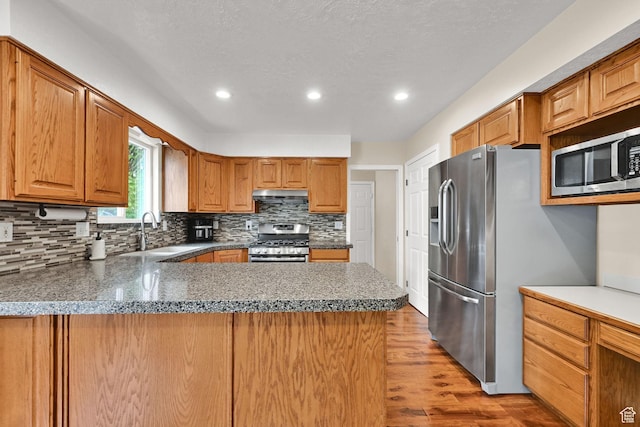 1780 N 800 E, North Ogden, UT 84414 - kitchen with stainless steel appliances, a sink, under cabinet range hood, backsplash, and wood finished floors