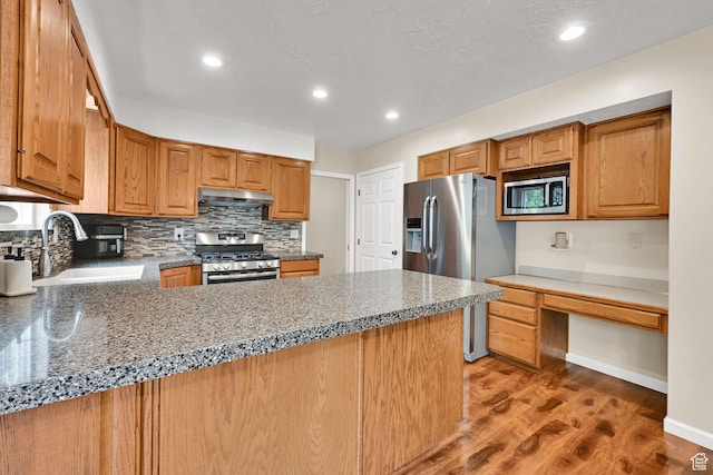 1780 N 800 E, North Ogden, UT 84414 - kitchen with appliances with stainless steel finishes, under cabinet range hood, a sink, light wood-style flooring, and tasteful backsplash