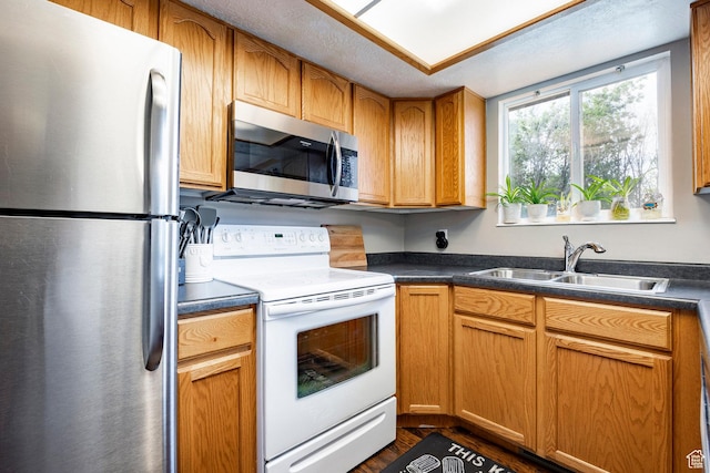 2135 W 4300 S, Roy, UT 84067 - kitchen with stainless steel appliances, a sink, dark countertops, dark wood finished floors, and brown cabinets