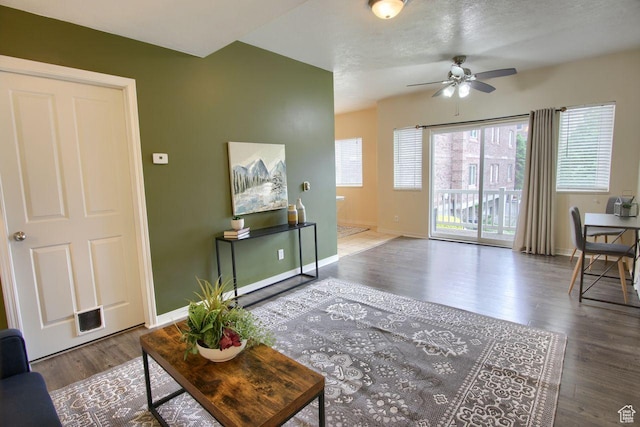 living area with a ceiling fan, wood finished floors, and baseboards