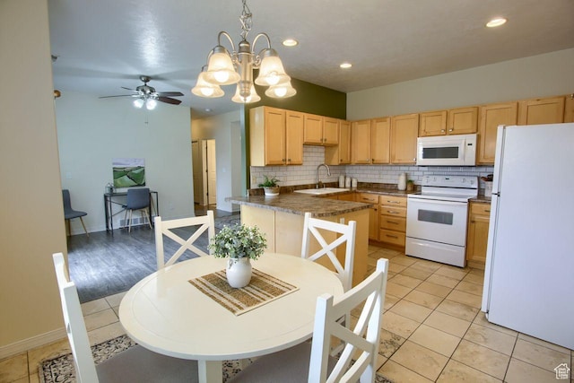 kitchen featuring white appliances, light brown cabinets, a sink, decorative backsplash, and a chandelier