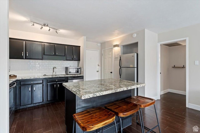 kitchen with a sink, dark wood-style floors, appliances with stainless steel finishes, and tasteful backsplash