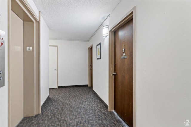 corridor featuring dark carpet, a textured ceiling, and baseboards
