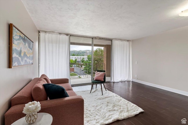 living room featuring a textured ceiling, baseboards, expansive windows, and dark wood-style flooring