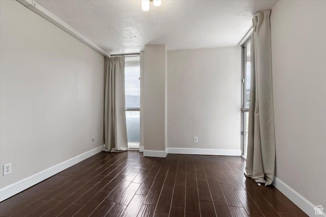 unfurnished room with baseboards and dark wood-style flooring