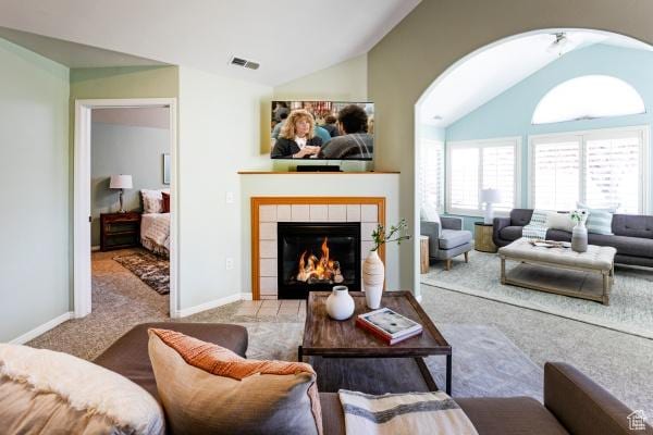 carpeted living area with lofted ceiling, a tiled fireplace, baseboards, and arched walkways