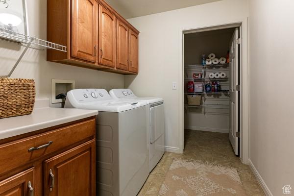 clothes washing area with cabinet space, washer and dryer, and baseboards
