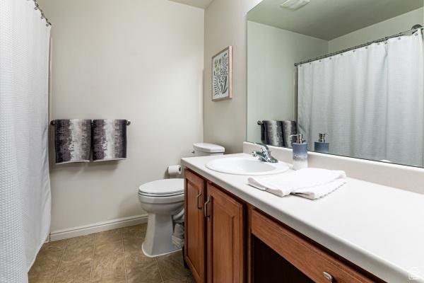 bathroom featuring vanity, toilet, baseboards, and tile patterned flooring