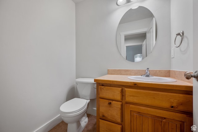 half bathroom featuring toilet, vanity, baseboards, and tile patterned flooring