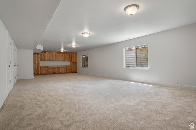 unfurnished living room with baseboards and light carpet