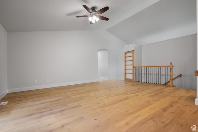 spare room with a ceiling fan, lofted ceiling, light wood-style floors, arched walkways, and baseboards