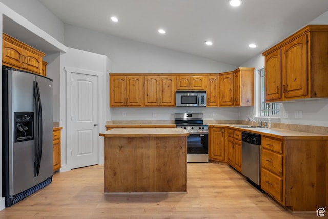 kitchen with appliances with stainless steel finishes, light countertops, a sink, lofted ceiling, and a kitchen island