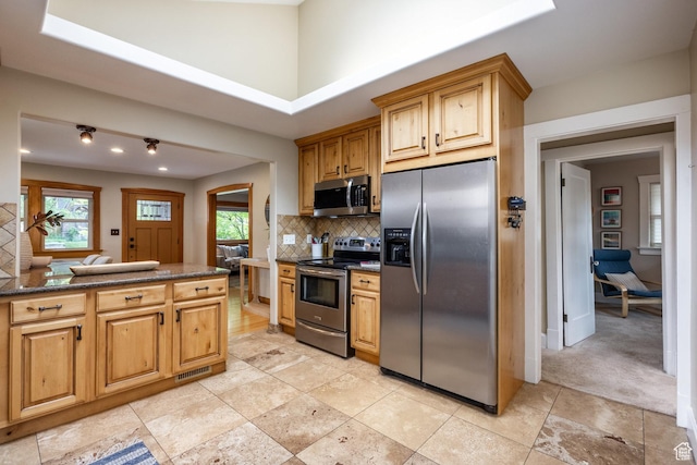 kitchen featuring stainless steel appliances, tasteful backsplash, healthy amount of natural light, dark stone counters, and recessed lighting