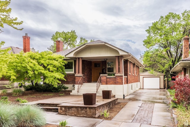 view of front facade featuring an outdoor structure, brick siding, a detached garage, and concrete driveway