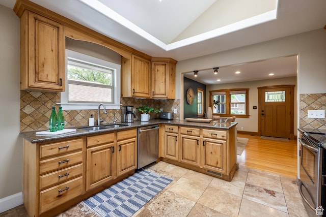 kitchen featuring appliances with stainless steel finishes, a sink, tasteful backsplash, a peninsula, and lofted ceiling