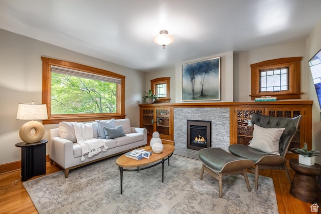 living area with wood finished floors, a lit fireplace, and baseboards