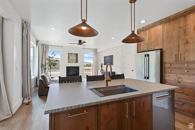 3232 E 5225 N, Eden, UT 84310 - kitchen featuring appliances with stainless steel finishes, a sink, open floor plan, an island with sink, and a glass covered fireplace