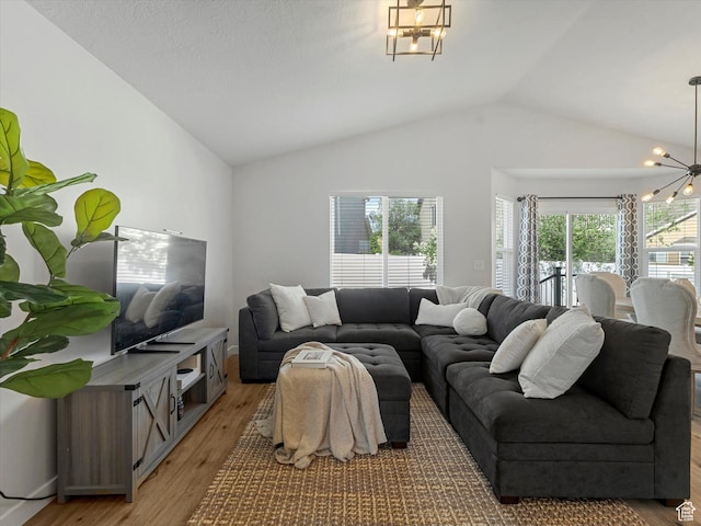living room featuring a chandelier, vaulted ceiling, and light wood finished floors