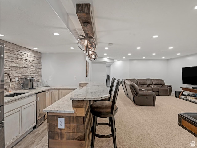 kitchen with a sink, light stone counters, recessed lighting, dishwasher, and open floor plan
