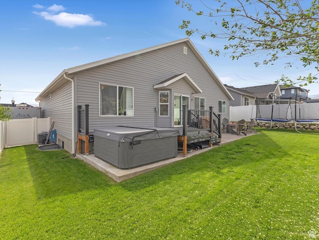 rear view of property featuring a trampoline and a hot tub