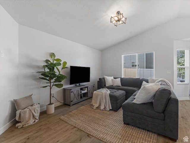living area featuring vaulted ceiling, wood finished floors, and baseboards