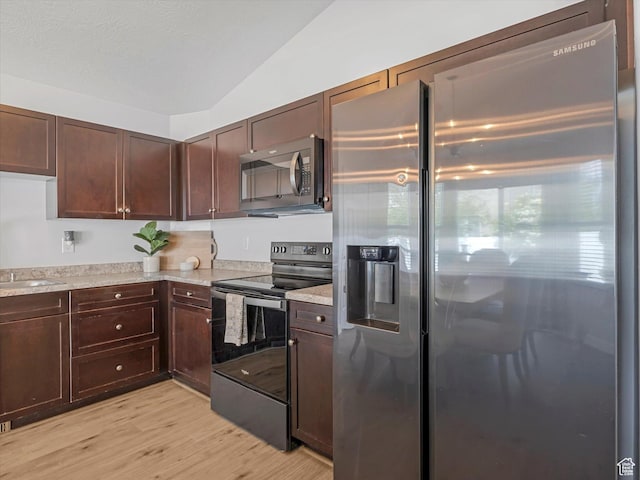 kitchen featuring stainless steel appliances, light countertops, light wood-style flooring, vaulted ceiling, and dark brown cabinets