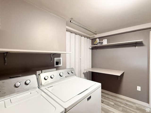 laundry area featuring washing machine and dryer, light wood-style flooring, and baseboards