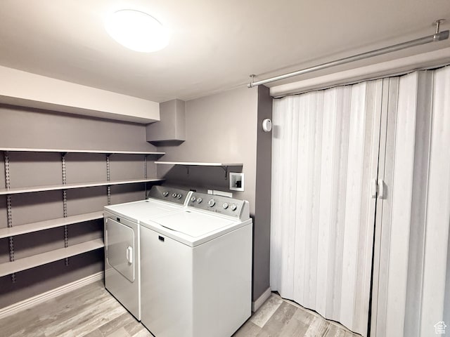 laundry room with washing machine and dryer, light wood-style floors, and baseboards