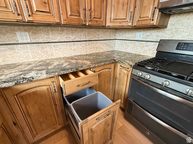 kitchen with range with two ovens, tasteful backsplash, and brown cabinetry