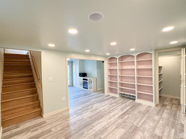 below grade area featuring recessed lighting, light wood-style floors, stairs, baseboards, and built in shelves