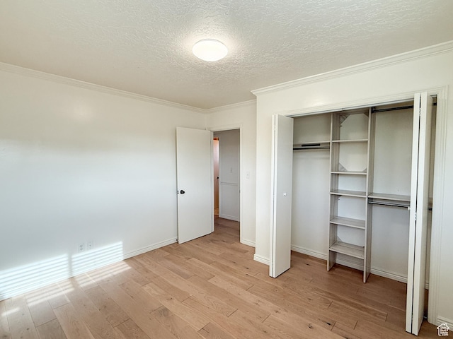 unfurnished bedroom featuring crown molding, light wood-style flooring, a textured ceiling, a closet, and baseboards