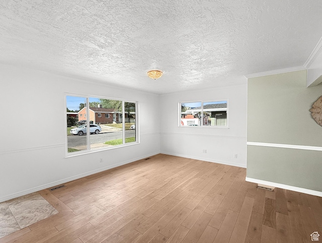 spare room with a textured ceiling, wood finished floors, and baseboards