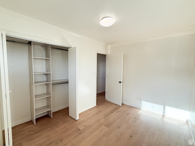 unfurnished bedroom with ornamental molding, light wood-style flooring, a closet, and baseboards