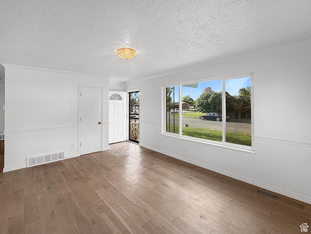 spare room with a textured ceiling, baseboards, and wood finished floors