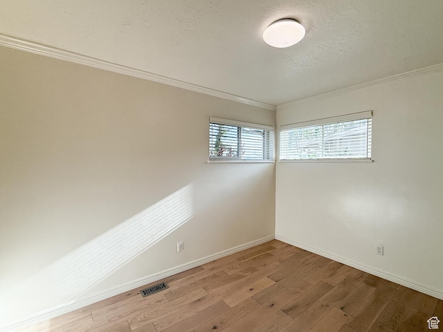 empty room featuring ornamental molding, baseboards, and light wood-type flooring