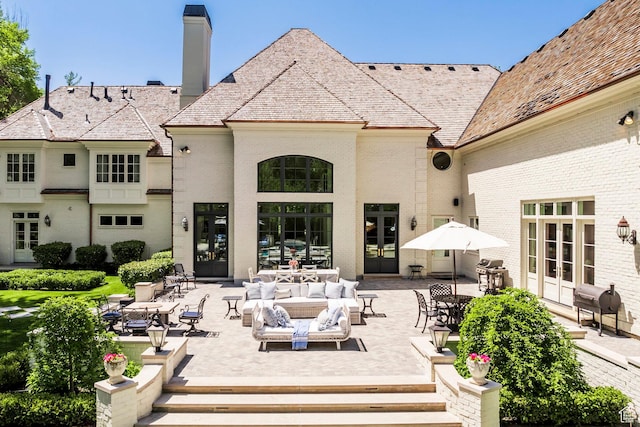 back of house with french doors, brick siding, outdoor lounge area, and a patio