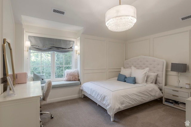 bedroom featuring a decorative wall, light carpet, a desk, and a chandelier