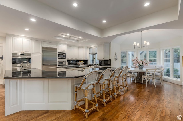 kitchen with built in appliances, dark countertops, dark wood finished floors, and recessed lighting