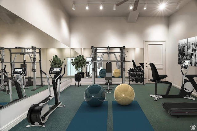 gym featuring track lighting, a high ceiling, and baseboards