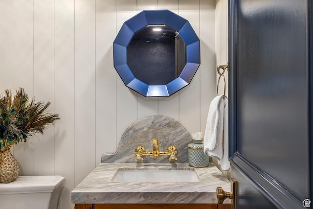 bathroom view of toilet, vanity, and a decorative wall