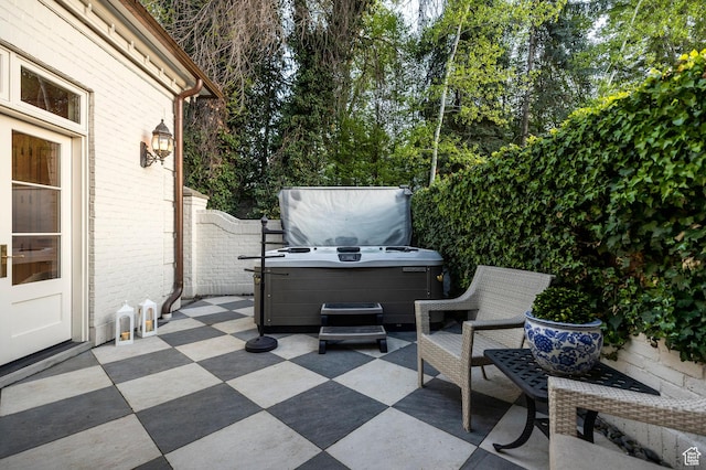 view of patio with a hot tub and fence