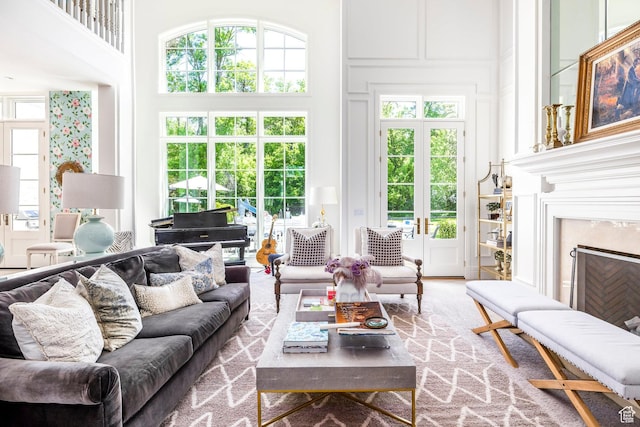 living room with a towering ceiling, a high end fireplace, and healthy amount of natural light