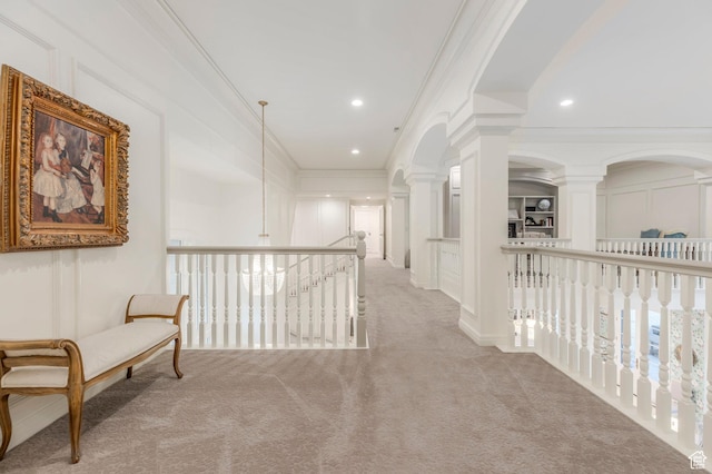 corridor featuring carpet floors, crown molding, decorative columns, recessed lighting, and a decorative wall