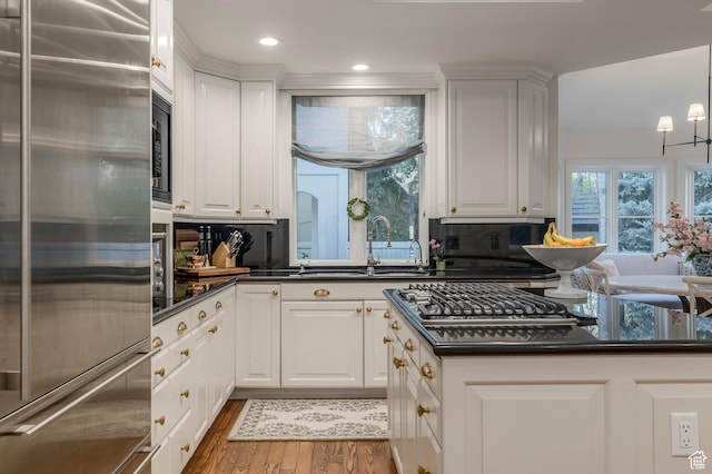 kitchen with stainless steel appliances, a sink, dark countertops, wood finished floors, and plenty of natural light